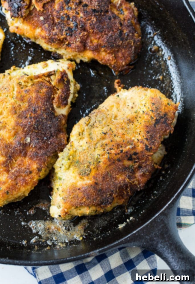 Three pieces of Pesto Pan-Fried Chicken on a wooden cutting board.
