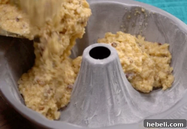 Transferring the finished batter to a greased bundt pan, ready for baking.