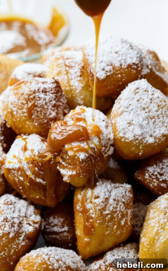 Golden Biscuit Fritters 6 A freshly fried Biscuit Beignet being removed from hot oil with a slotted spoon, golden and puffy