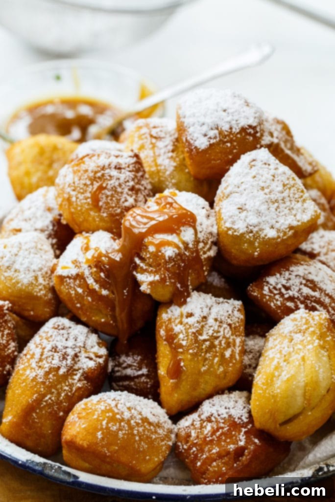 Golden Biscuit Fritters 7 A plate of finished Biscuit Beignets generously covered in powdered sugar, ready to be enjoyed with a cup of coffee