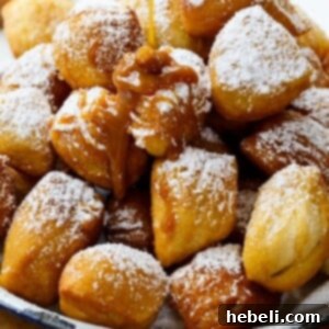 Close-up of a stack of golden Biscuit Beignets, dusted with powdered sugar and ready to eat