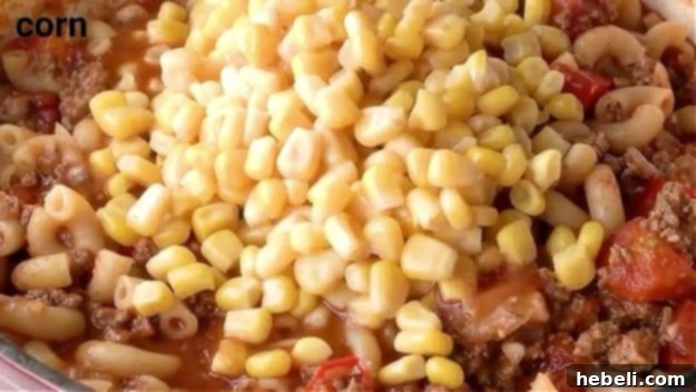 Stirring in corn as the final step before serving Southern Goulash.