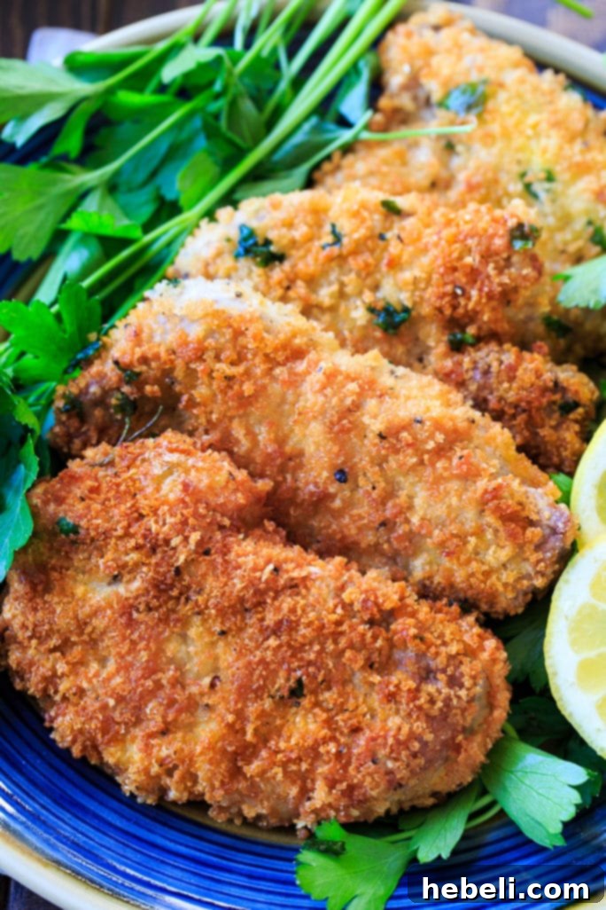 Crispy Pork Milanese 3 Pork Milanese cutlets being pounded thin on a cutting board