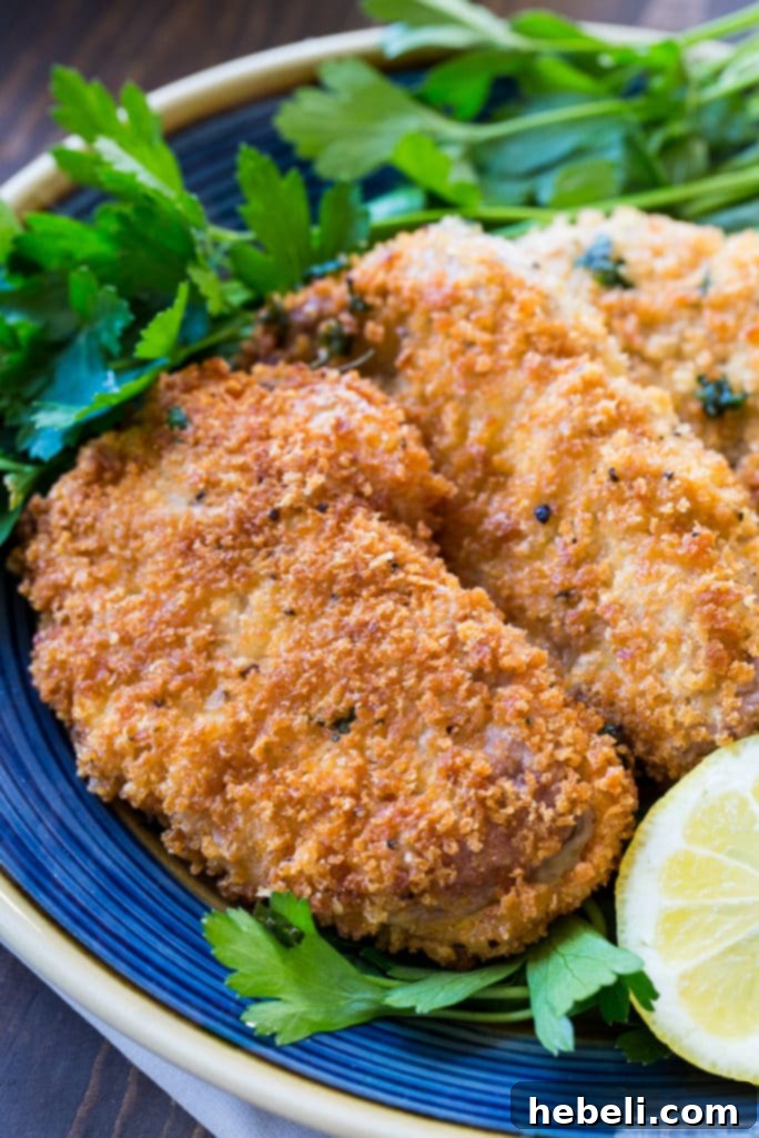Crispy Pork Milanese 4 Pork Milanese cutlets frying in a skillet with olive oil