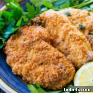 Pork Milanese finished dish with lemon wedges and parsley