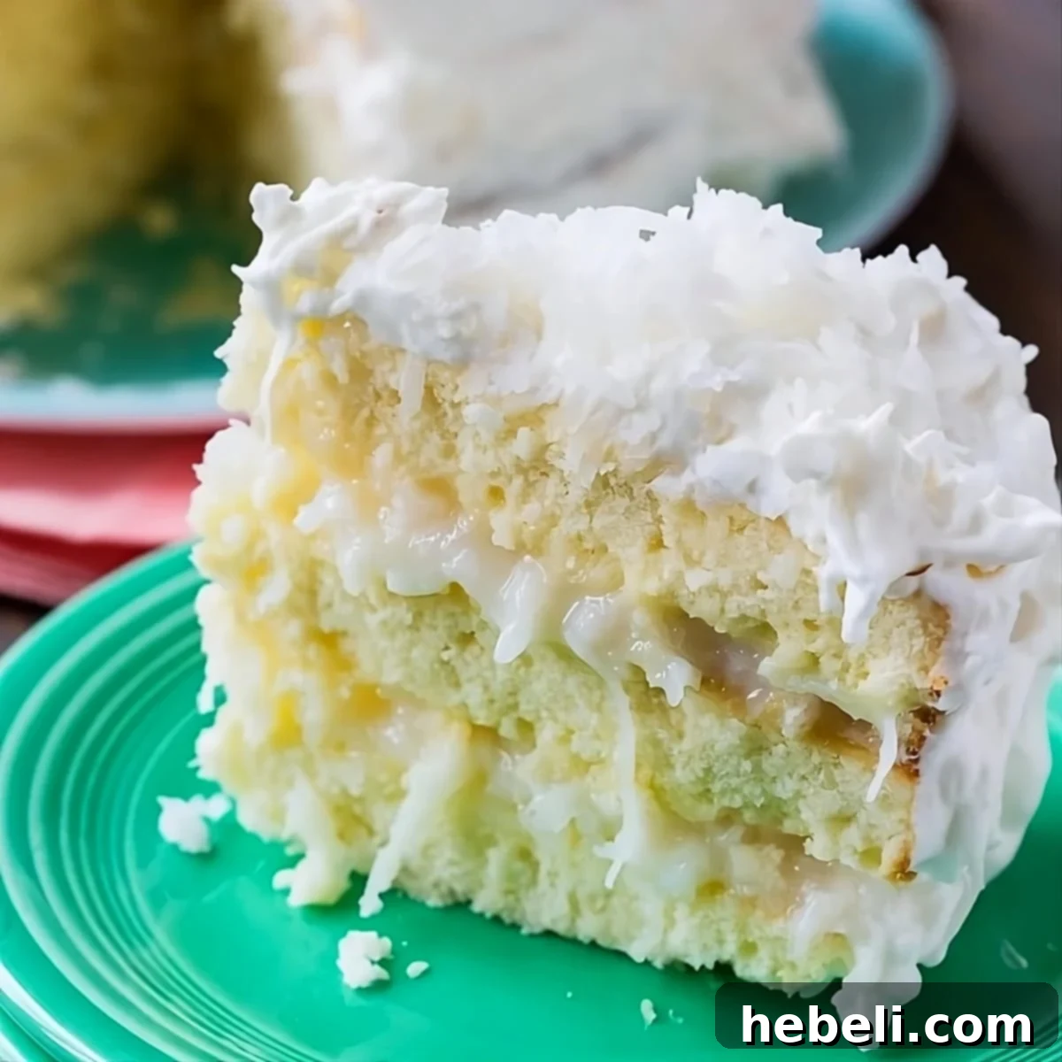 A delectable slice of Coconut Celebration Cake on a pristine white plate, showcasing its moist layers and creamy frosting.