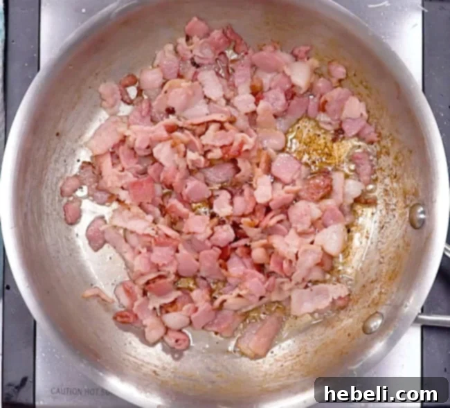 Chopped bacon cooking in a hot skillet, sizzling and turning crispy.