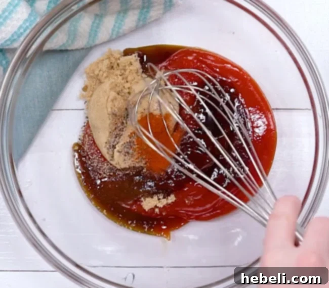 A bowl with a whisk, mixing ketchup, brown sugar, BBQ sauce, and other ingredients for the sauce.