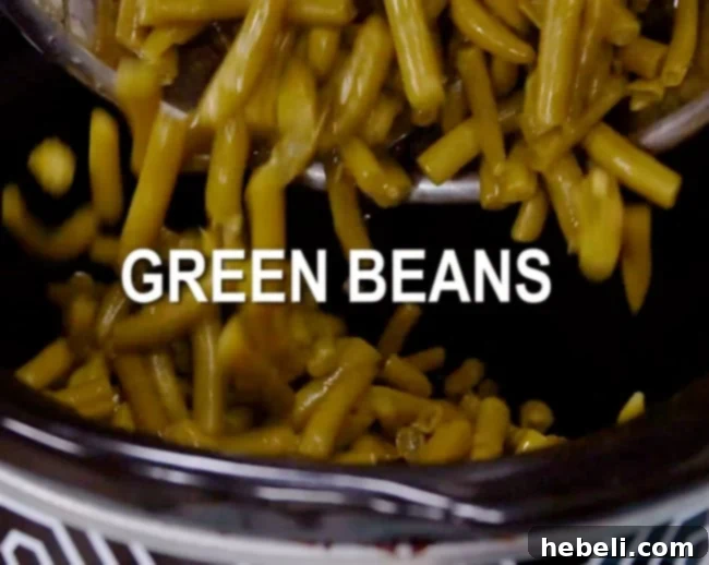 Drained canned green beans being added to a slow cooker.
