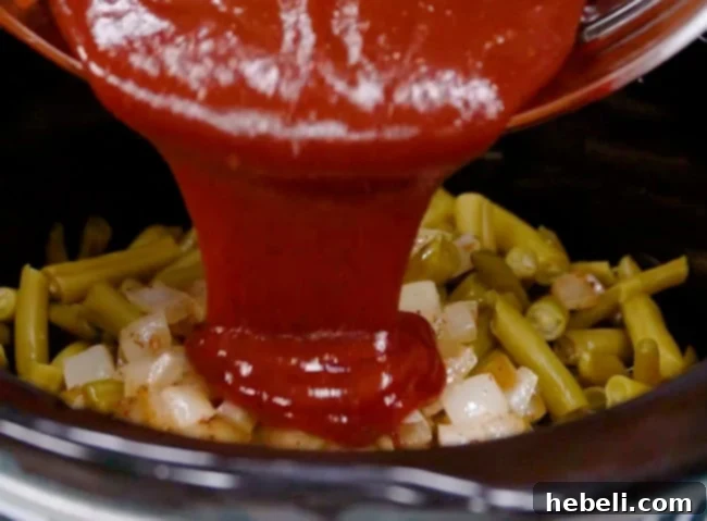 Pouring the mixed ketchup and BBQ sauce over the green beans in the slow cooker.