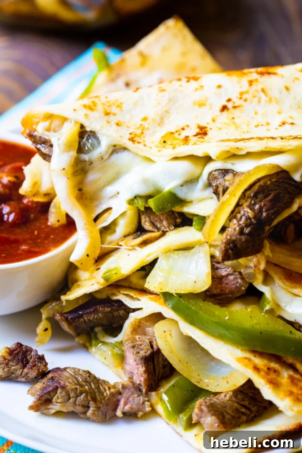 Philly Cheese Steak Quesadillas on a plate with a side of salsa, ready to be served.