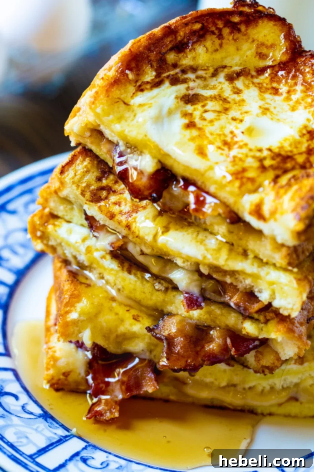 Close-up of golden brown French Toast Stuffed with Bacon, piled high with maple syrup dripping down