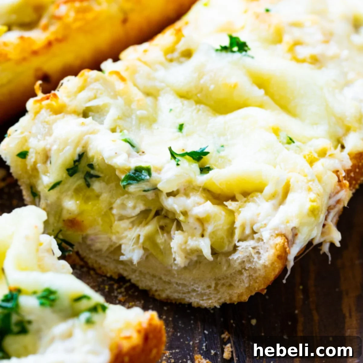 Artichoke and Crab Dip Bread with a tempting slice cut out, showcasing its cheesy, creamy interior.