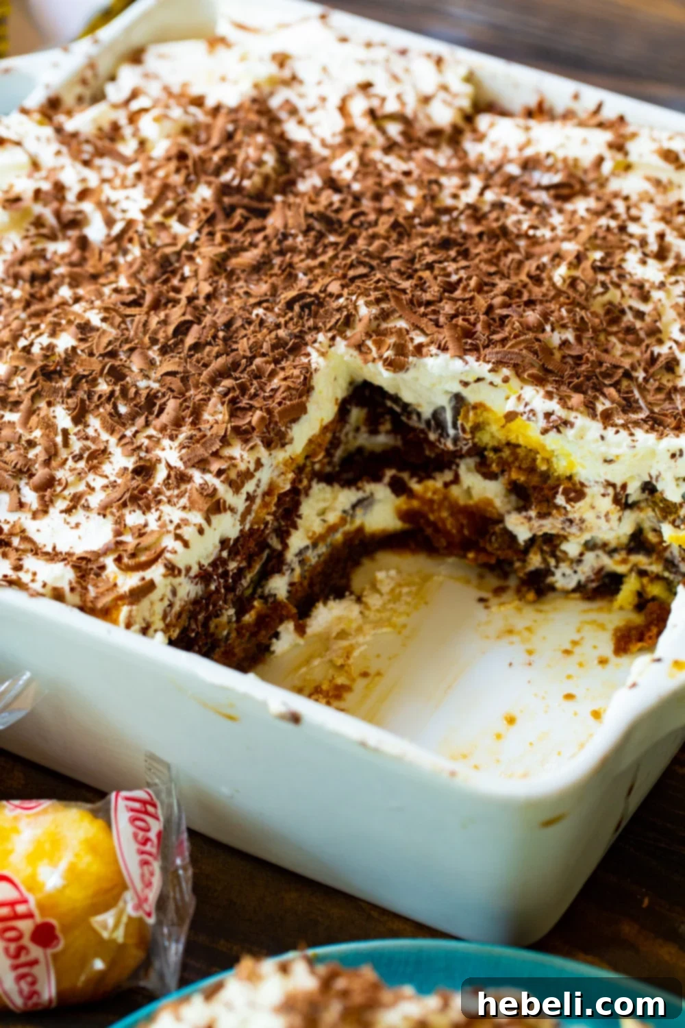A square serving dish of Twinkie Tiramisu with a piece removed, revealing the delicious internal layers of Twinkie, cream, and chocolate.