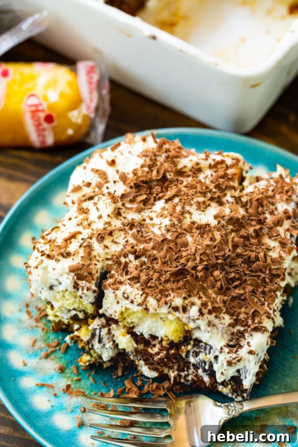 A slice of creamy Twinkie Tiramisu on a vibrant blue plate, garnished with chocolate shavings.