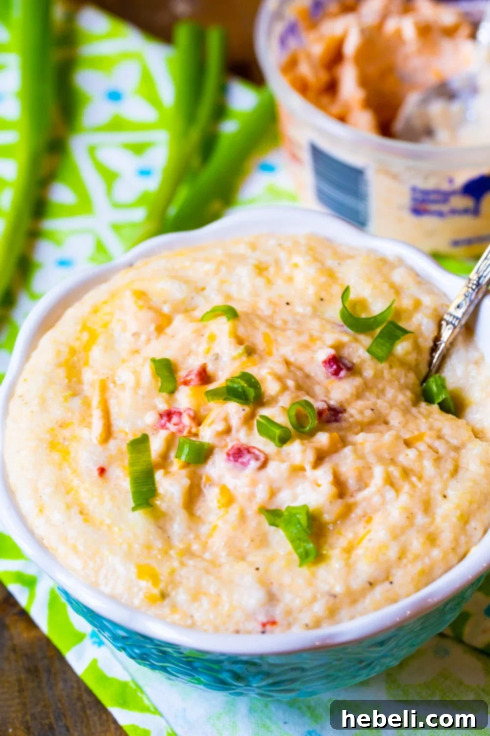 Creamy Pimento Cheese Grits 3 Close-up shot of creamy grits mixed with pimento cheese, served in an elegant blue bowl, highlighting its rich texture.