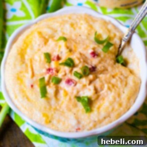 Creamy Pimento Cheese Grits 6 Pimento Cheese Grits in a bowl with a spoon, highlighting the rich, creamy texture.