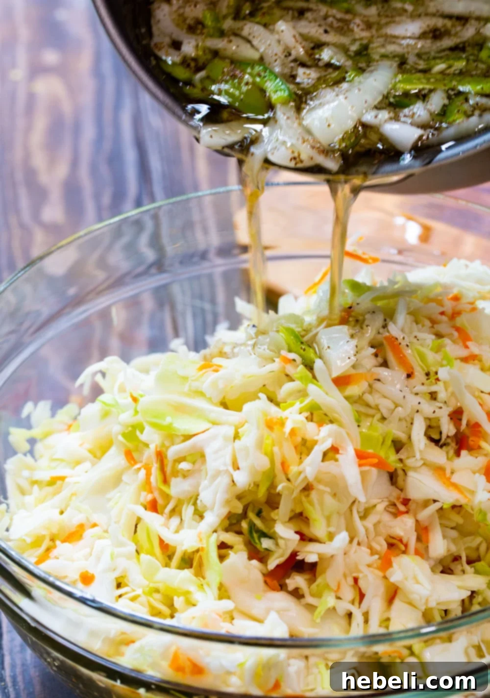 Delightfully Sweet Vinegar Slaw 4 Hot vinegar mixture being poured into a large bowl with shredded cabbage for coleslaw.