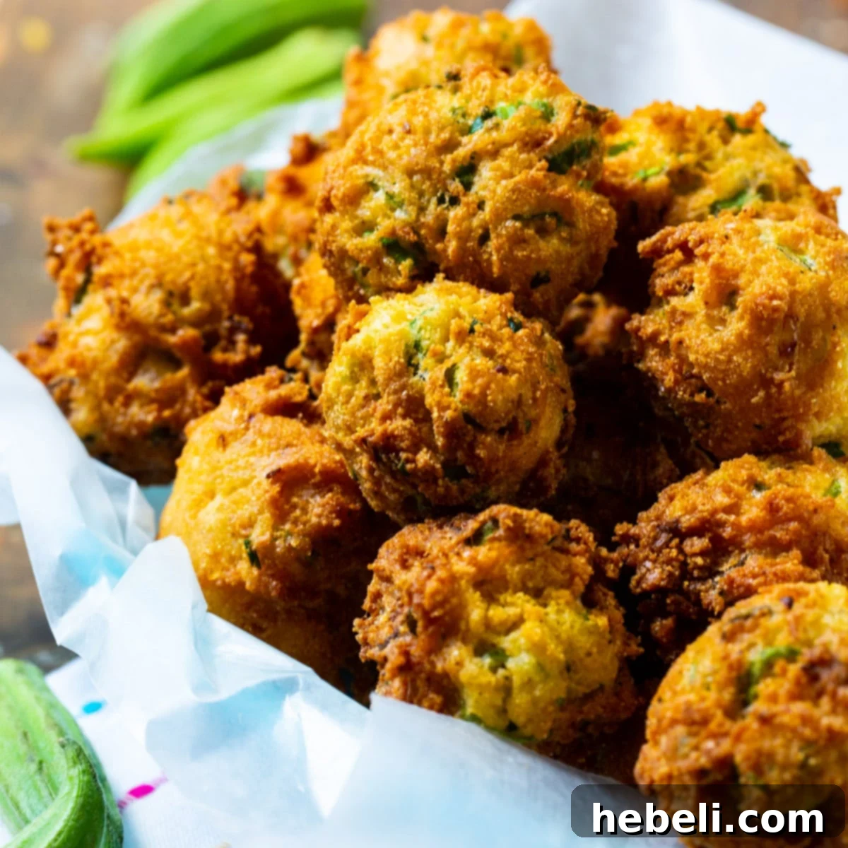 Southern Okra Hushpuppies 2 A rustic basket filled with golden-brown Okra Hush Puppies, garnished with fresh herbs, ready to be served.