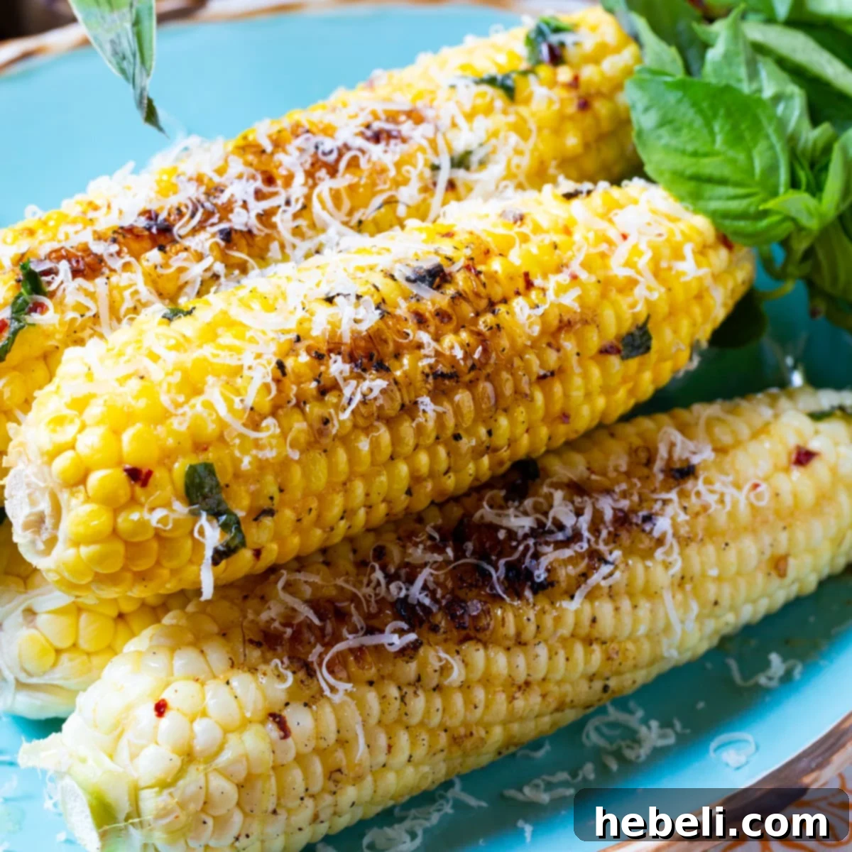 Grilled Garlic Parmesan Corn with fresh basil, ready to be served at a summer gathering.
