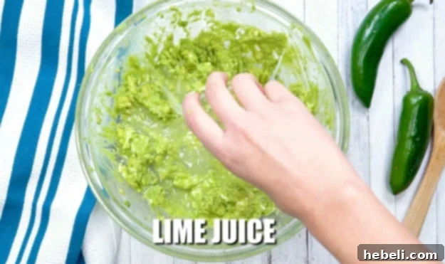 Adding fresh lime juice to the mashed avocado and cream cheese mixture.