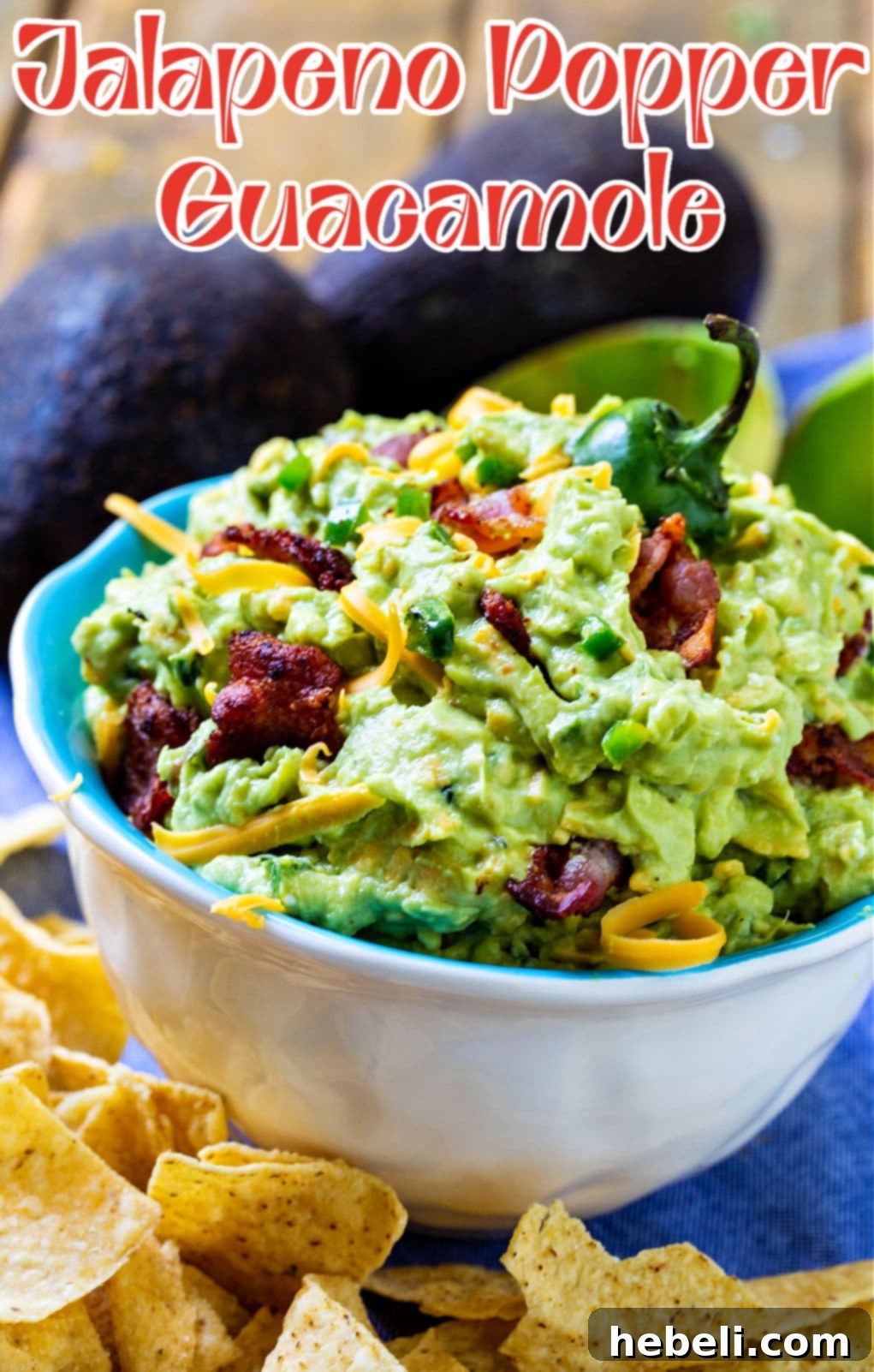 Close-up shot of homemade Jalapeno Popper Guacamole in a decorative bowl, garnished with a whole jalapeño and served with crunchy tortilla chips.