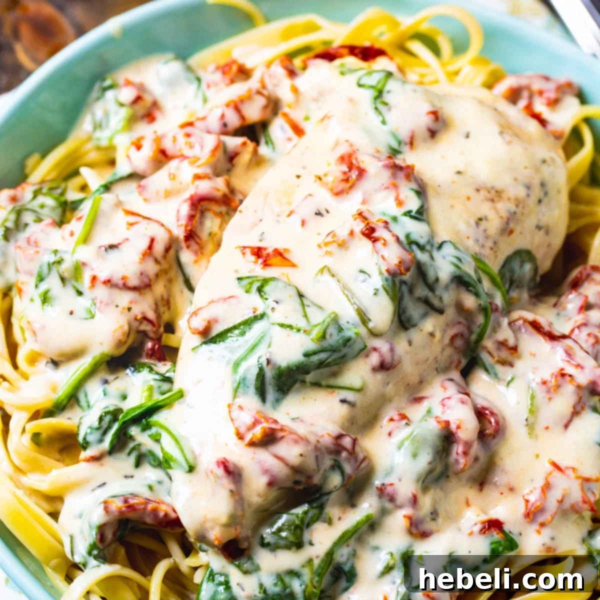 Velvety Slow Cooker Tuscan Chicken 2 Slow Cooker Creamy Tuscan Chicken served over pasta in a beautiful white bowl, garnished with fresh herbs.