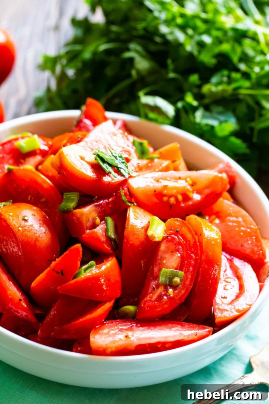 Zesty Marinated Tomatoes 3 A bowl of Marinated Tomatoes garnished with fresh parsley, alongside a bunch of raw parsley.
