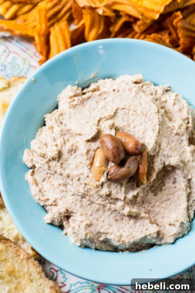 Fiery Boiled Peanut Dip 3 Close-up shot of creamy Spicy Boiled Peanut Hummus garnished with a sprinkle of paprika and fresh parsley, highlighting its smooth texture.