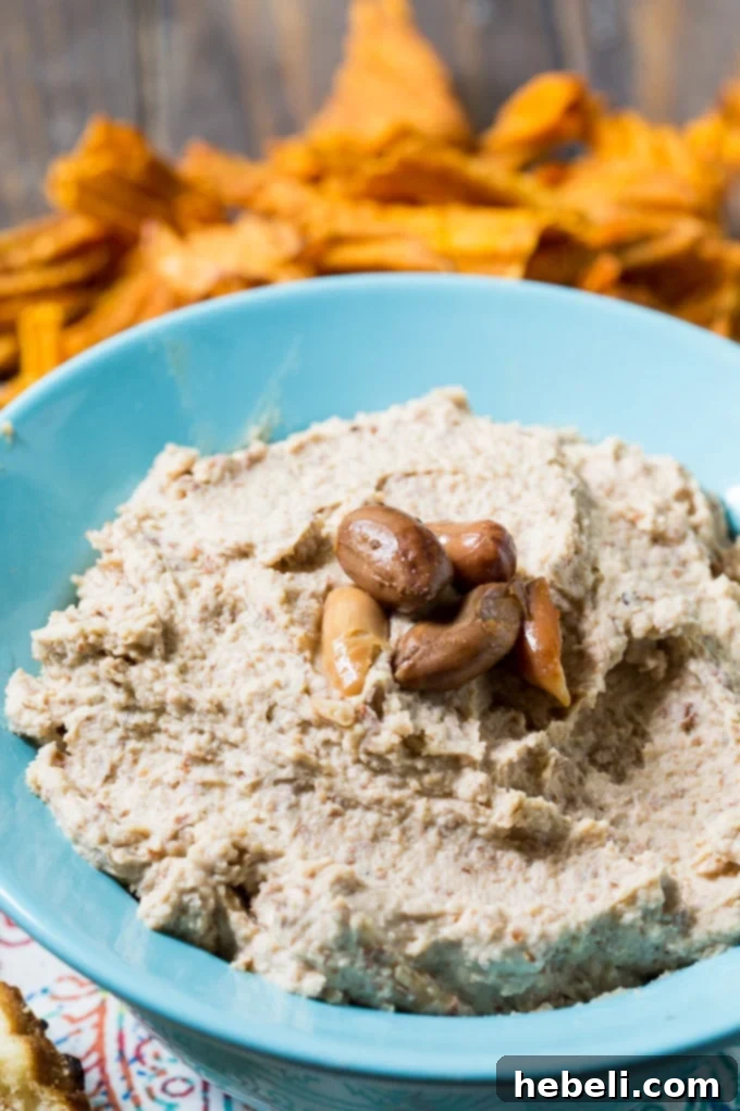 Fiery Boiled Peanut Dip 5 A top-down view of Spicy Boiled Peanut Hummus in a bowl, with a drizzle of oil and a sprig of fresh herb for garnish, ready for serving.