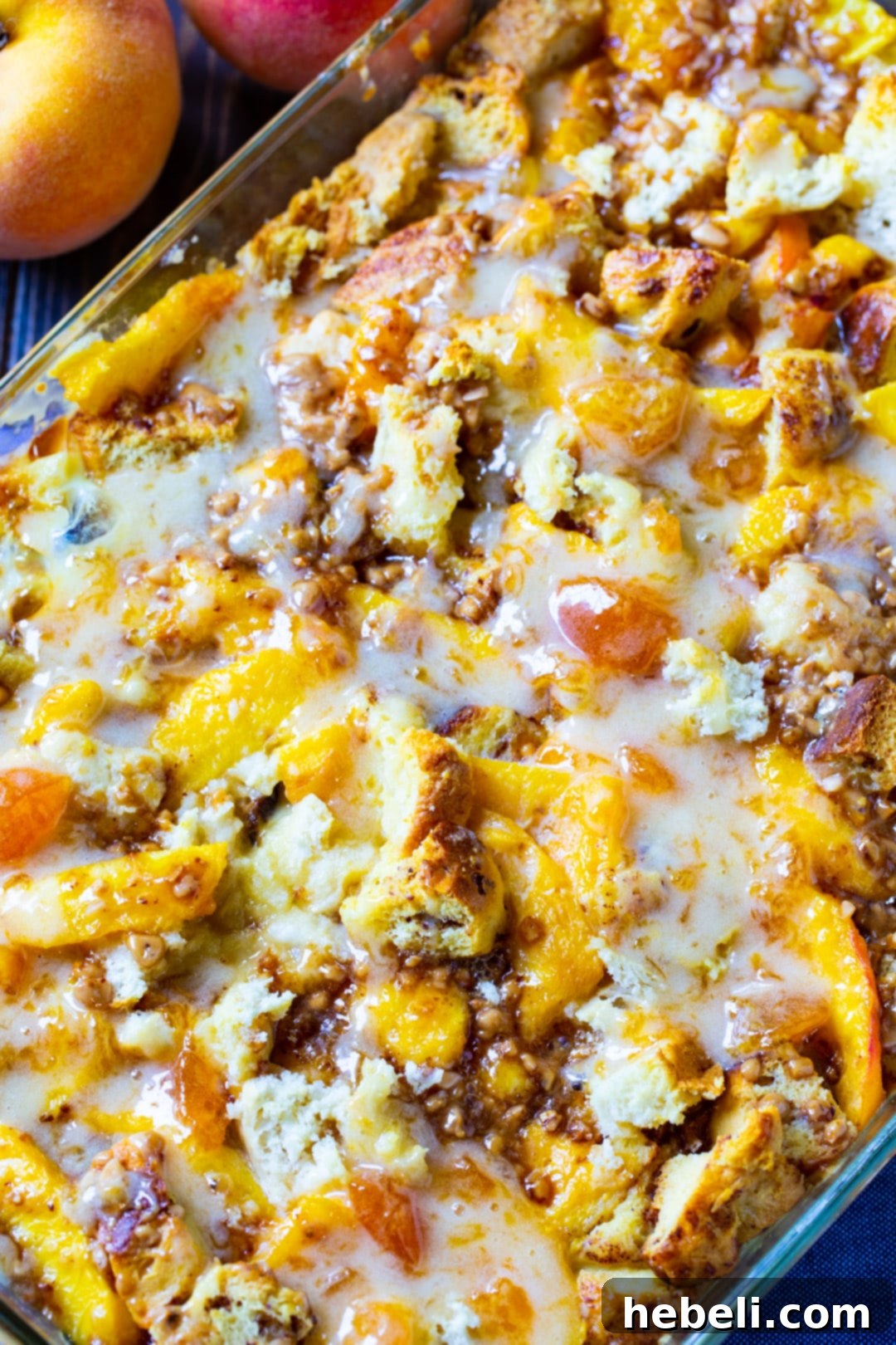 Comforting Peach Cinnamon Bread Pudding 4 A close-up view of the golden-brown Cinnamon-Peach Bread Pudding in its baking dish, revealing the custardy texture and peach pieces, before being drizzled with glaze.