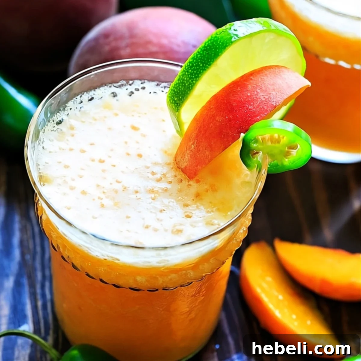 Sweet Heat Peach Margarita 2 A beautifully crafted Peach Jalapeno Margarita in a cocktail glass, garnished with a peach slice and a jalapeño wheel.