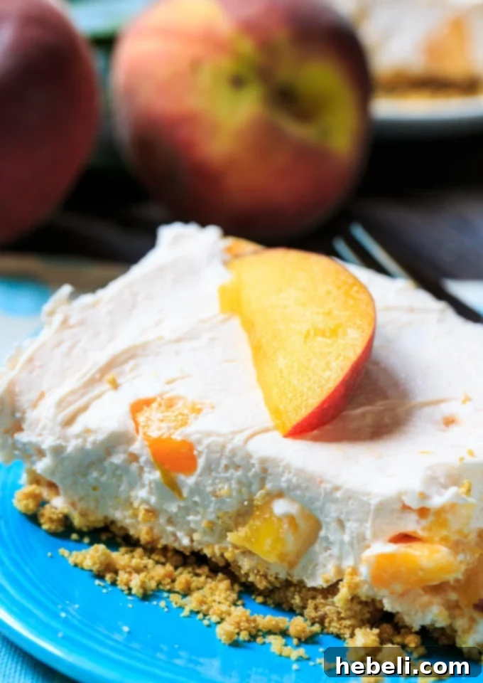 Individual serving of No-Bake Peach Cheesecake Bar garnished with fresh peach slices and a mint leaf
