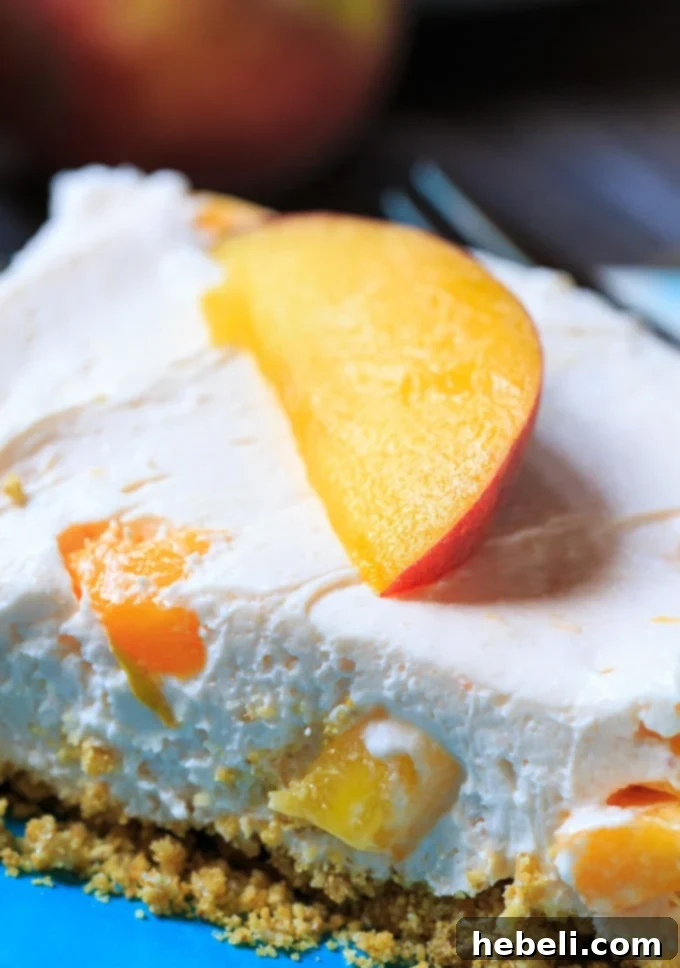 Overhead view of a tray of freshly made No-Bake Peach Cheesecake Bars ready to be served, garnished with fresh peaches