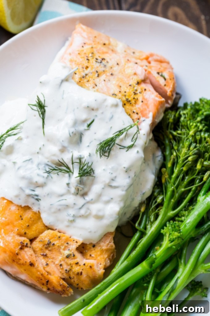 Baked salmon covered in creamy dill sauce, garnished with fresh dill