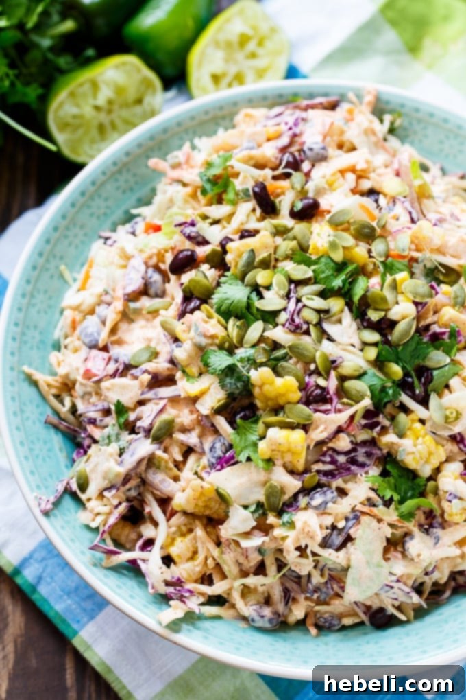 Close-up of colorful Mexican-flavored coleslaw with visible black beans, corn, red pepper, and cilantro.