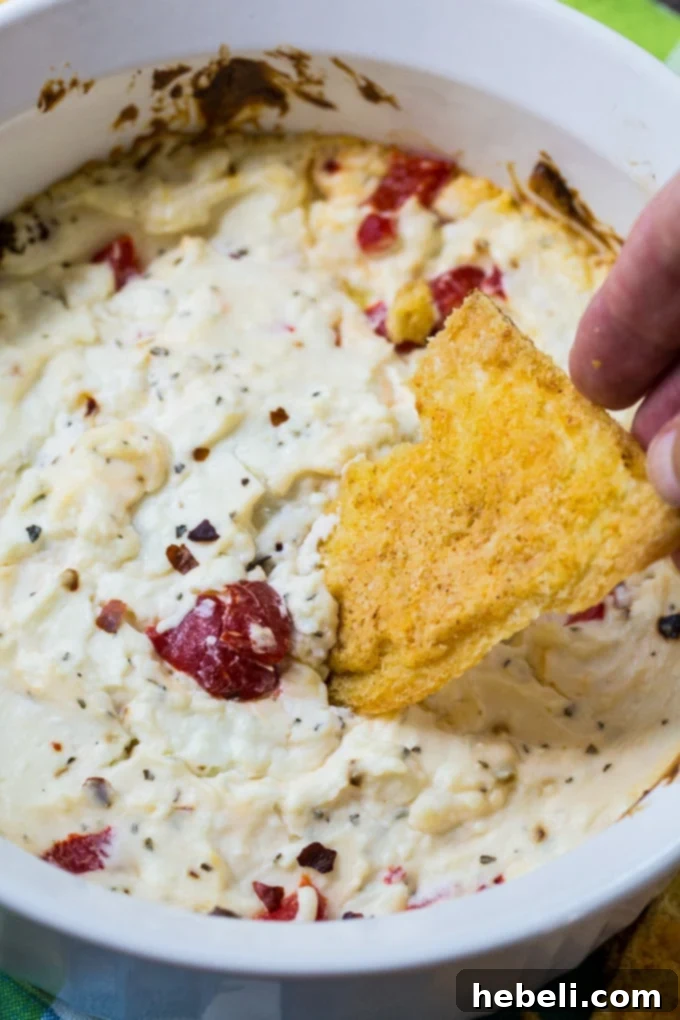 Oven-Baked Spicy Feta Cheese Dip served with various dippers like pita bread and fresh vegetables on a rustic wooden board.