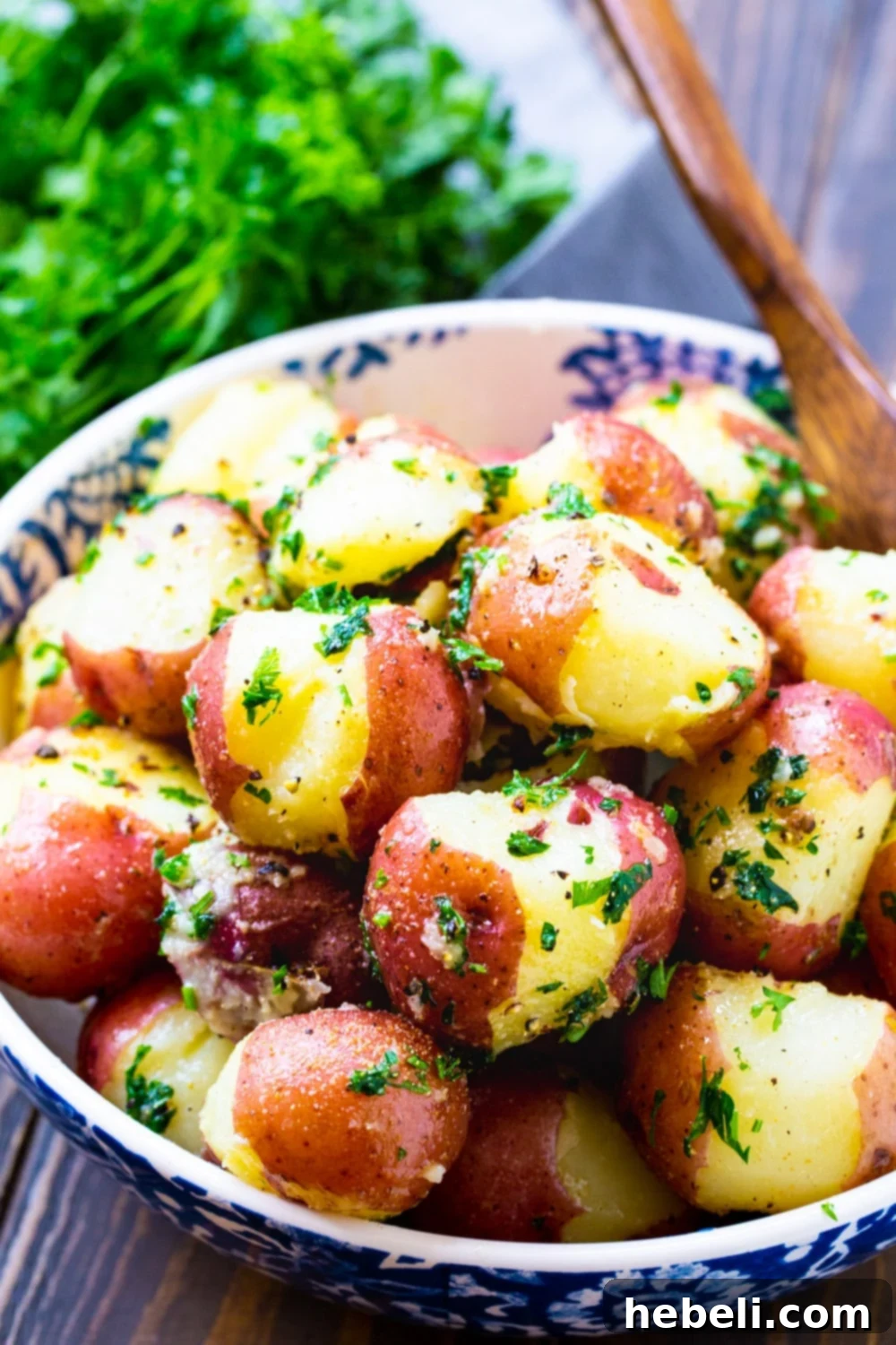 Butter Parsley Potatoes in a bowl with a fresh bunch of parsley beside it.
