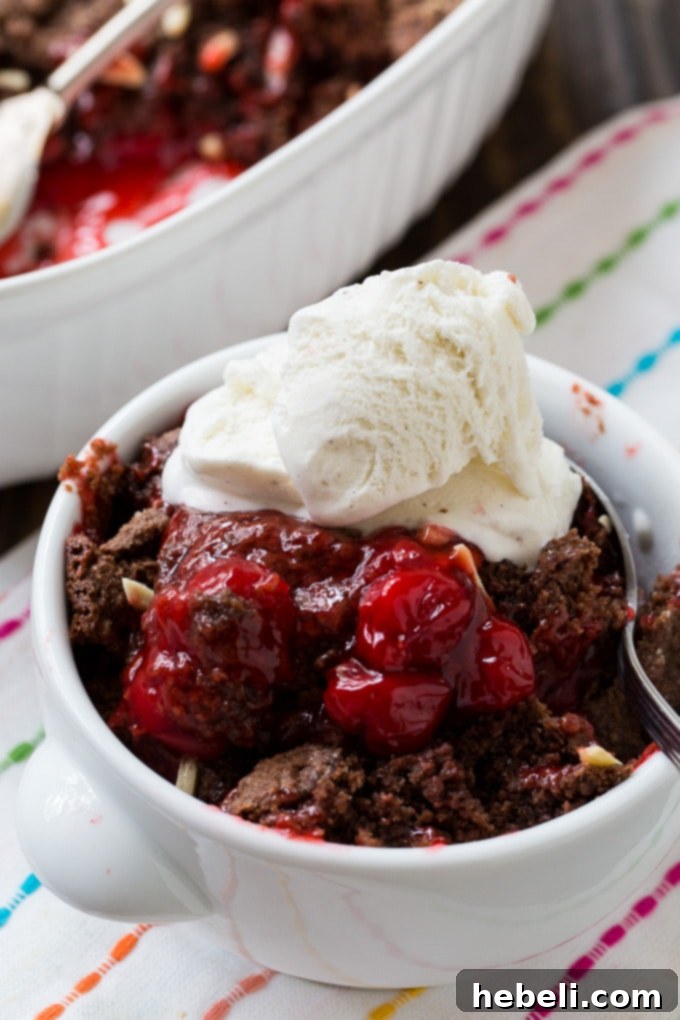 Warm Chocolate Cherry Cobbler served with a scoop of melting vanilla ice cream in a bowl.