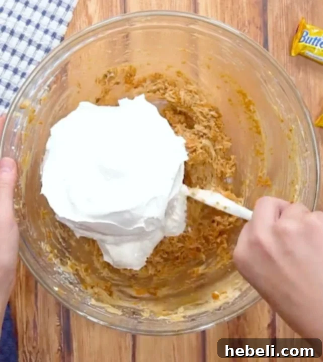 Adding Cool Whip to the pie filling.