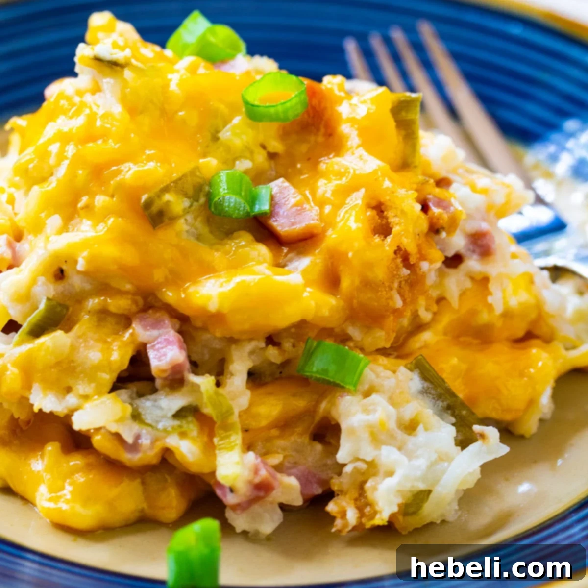 A serving of cheesy ham and hash brown casserole on a plate, ready to be enjoyed for breakfast or brunch.