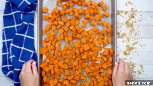 Sweet Heat Roasted Sweet Potatoes 4 Sweet potato cubes spread out in a single layer on a baking sheet, ready for roasting