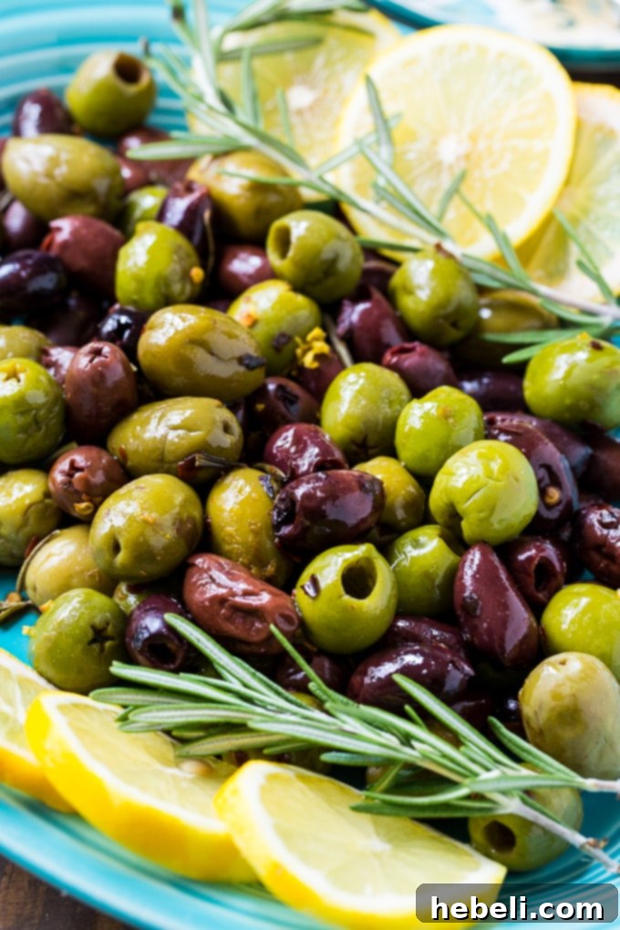 An appetizing spread of party foods including Warm Rosemary Olives, a cheese platter, and a bowl of Cajun nuts.