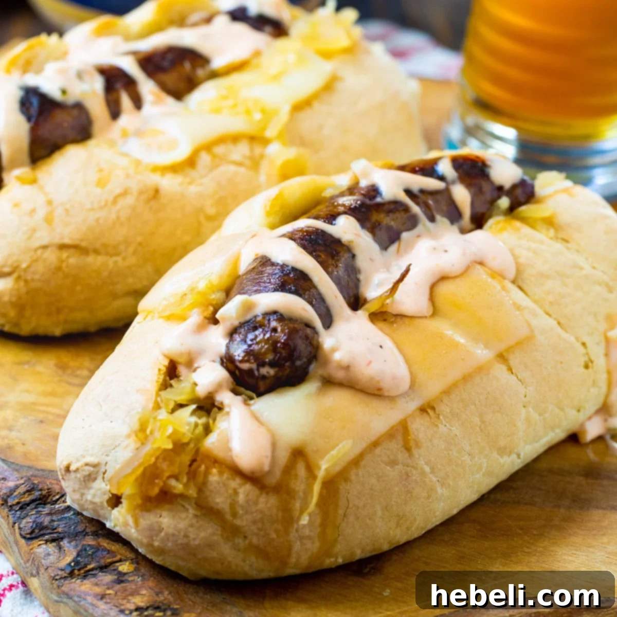 Easy Slow Cooker Reuben Brats 2 Two perfectly assembled Crock Pot Reuben Brats in toasted buns, showcasing melted cheese, sauerkraut, and a drizzle of Thousand Island dressing.
