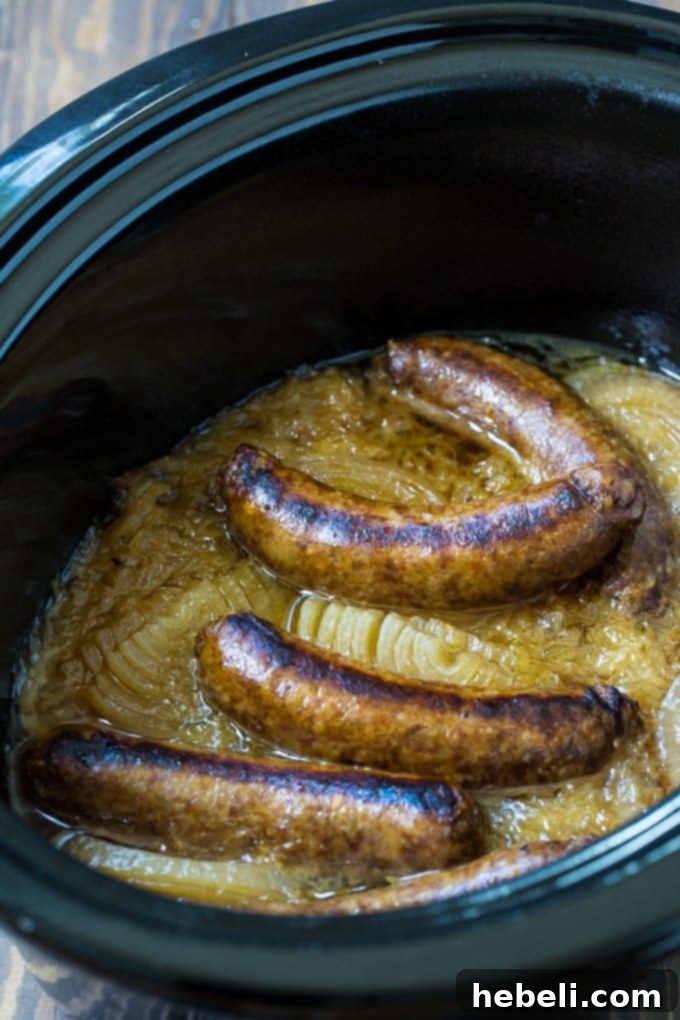 Easy Slow Cooker Reuben Brats 3 A close-up view of a single Crock Pot Reuben Brat, emphasizing the succulent bratwurst, vibrant sauerkraut, and melted cheese inside a bun.
