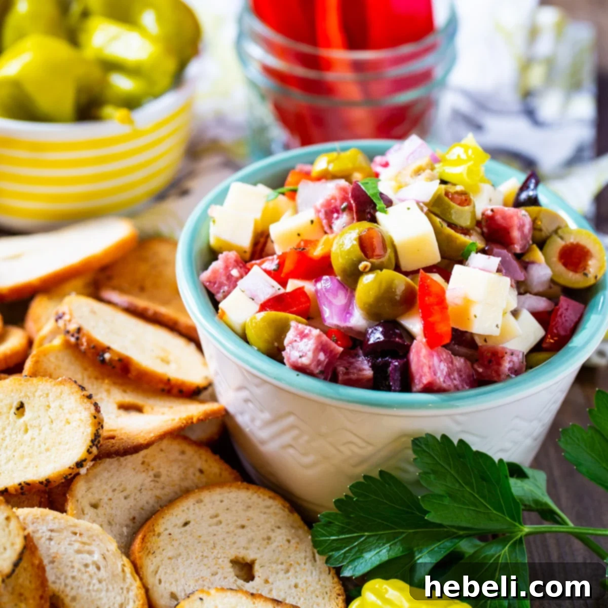 Muffaletta Dip in a small bowl surrounded by bagel chips.