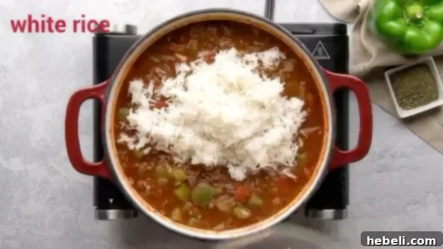 Cooked white rice being added to the Stuffed Pepper Soup in the Dutch oven.
