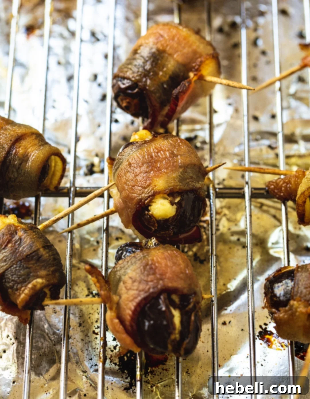 Sweet and Savory Bacon Wrapped Stuffed Dates 4 Tray of cooked Bacon Wrapped Stuffed Dates cooling on a wire rack after baking.