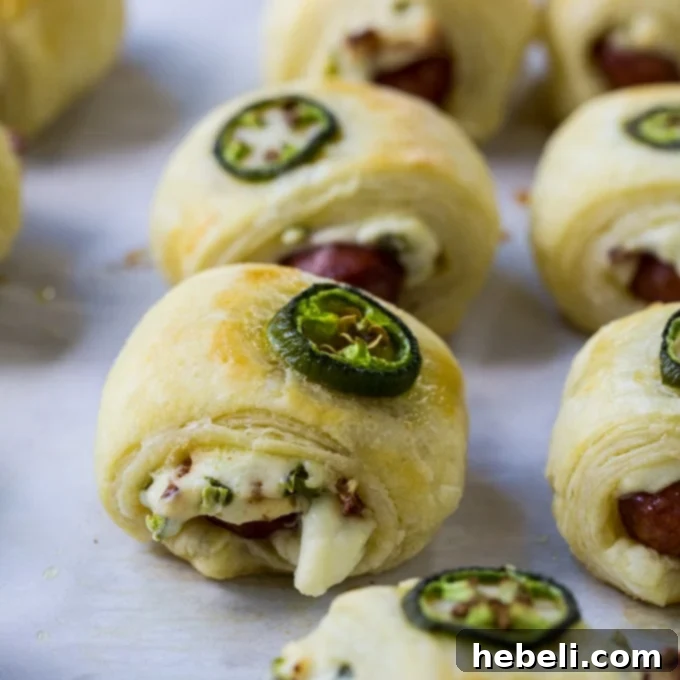 Spicy Piggy Poppers 3 Close-up of a single Jalapeno Popper Pig in a Blanket, showing the flaky pastry and vibrant green jalapeño.