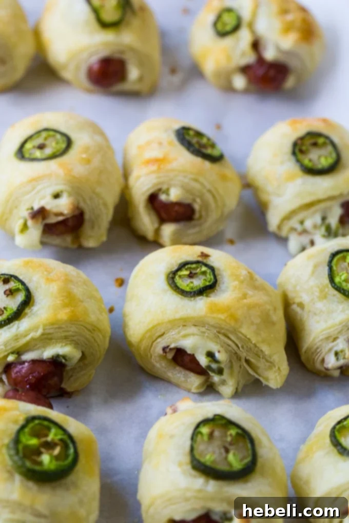 Spicy Piggy Poppers 4 Ingredients for Jalapeno Popper Pigs in a Blanket laid out on a cutting board, including puff pastry, cocktail wieners, cream cheese, bacon, and fresh jalapeños.